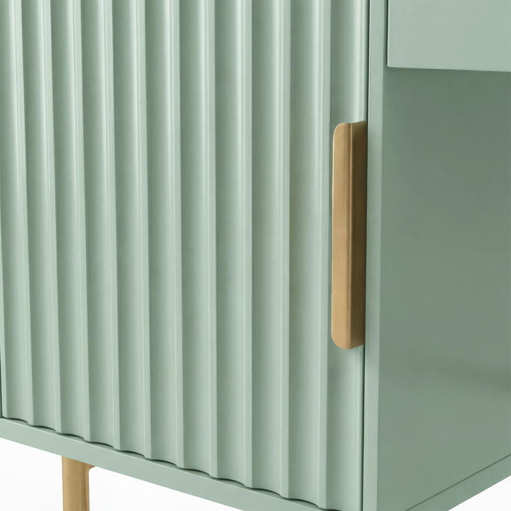 [Sage Green] detail of the sage green painted fluted door with a pale-wood pull and a gold tube leg below