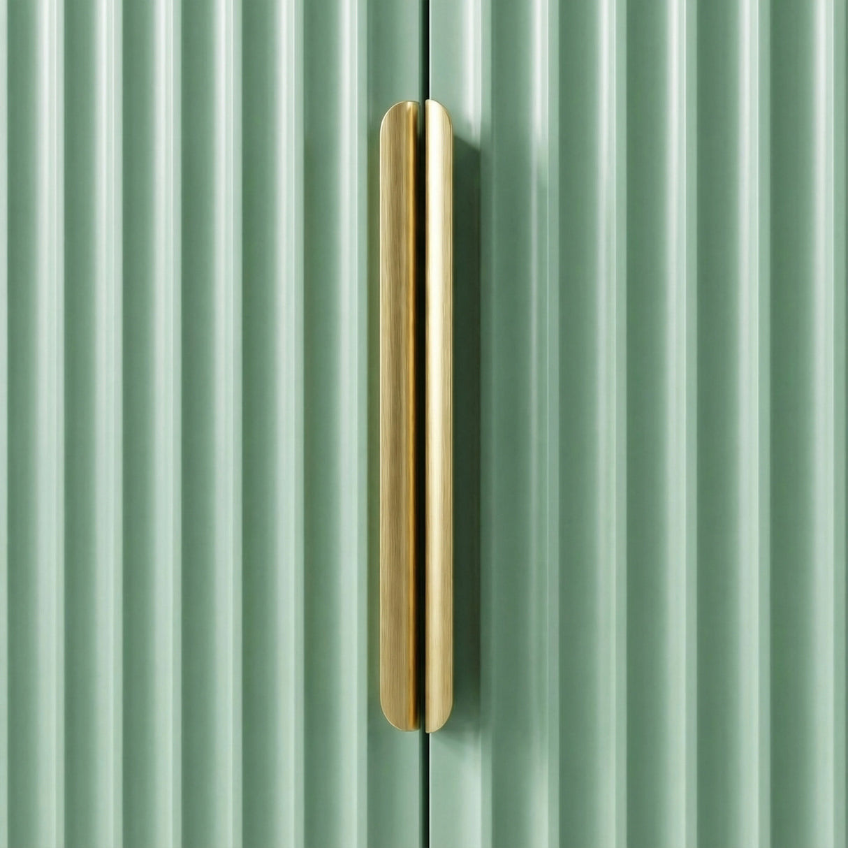 Green flutrina wardrobe with vertical golden metal handle close up on painted door surface
