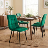 [Green | Set of 4] Velvet dining chair in front of a table, with a curved tufted back, black legs and matching chairs behind.