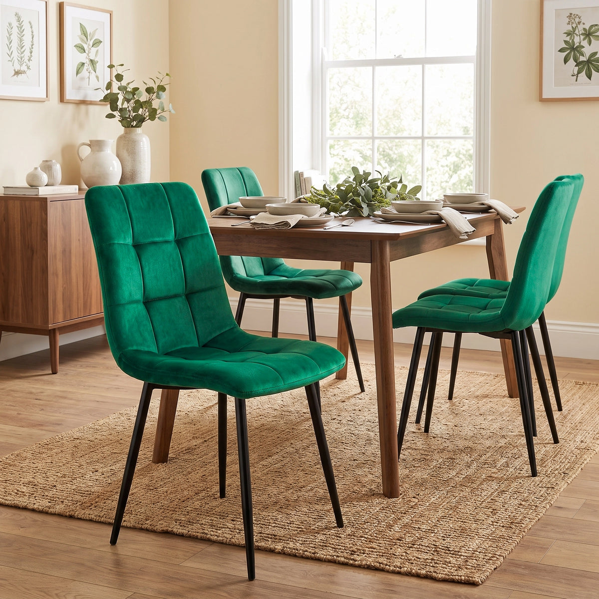 [Green | Set of 4] Velvet dining chair in front of a table, with a curved tufted back, black legs and matching chairs behind.