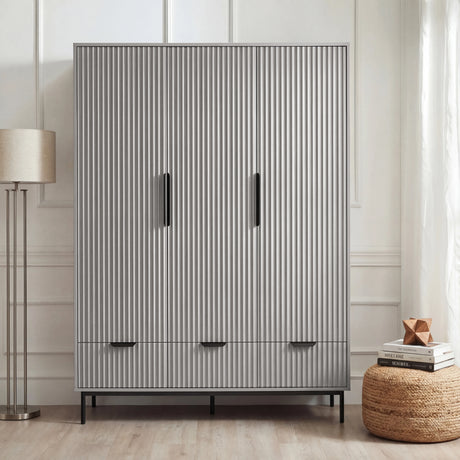 Grey flutrina design triple wardrobe with drawers and black handles placed against a wall in a bedroom