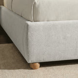 Close-up detail of the bottom base of the grey king upholstered bed frame with rounded wooden feet