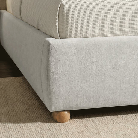 Close-up detail of the bottom base of the grey king upholstered bed frame with rounded wooden feet