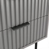 Close detail of the black metallic handle fixed to the grey flutrina design drawer surface of a nightstand