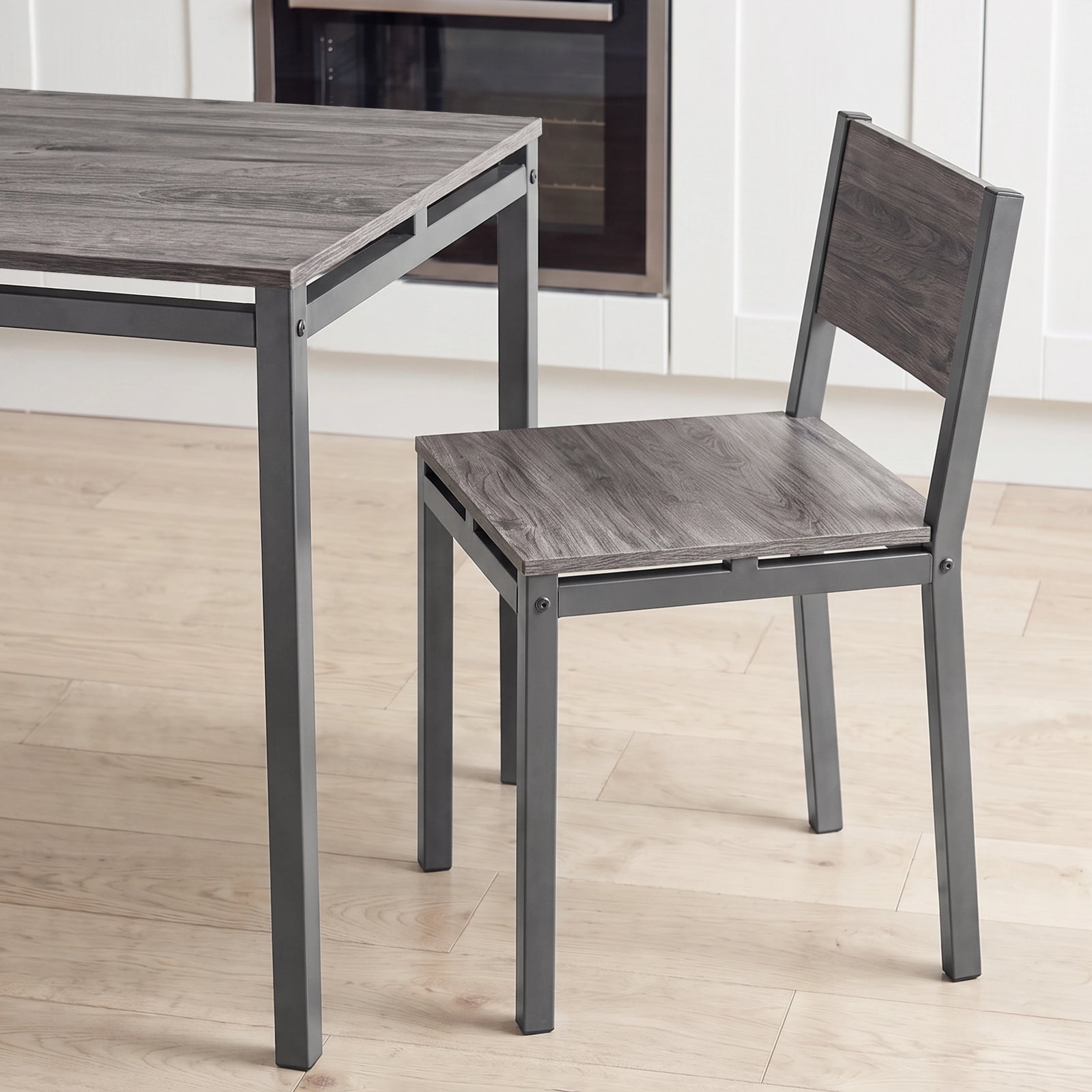 [Grey] Breakfast table edge & chair close-up with wood-effect panels, square grey metal frames, support rails & visible bolts