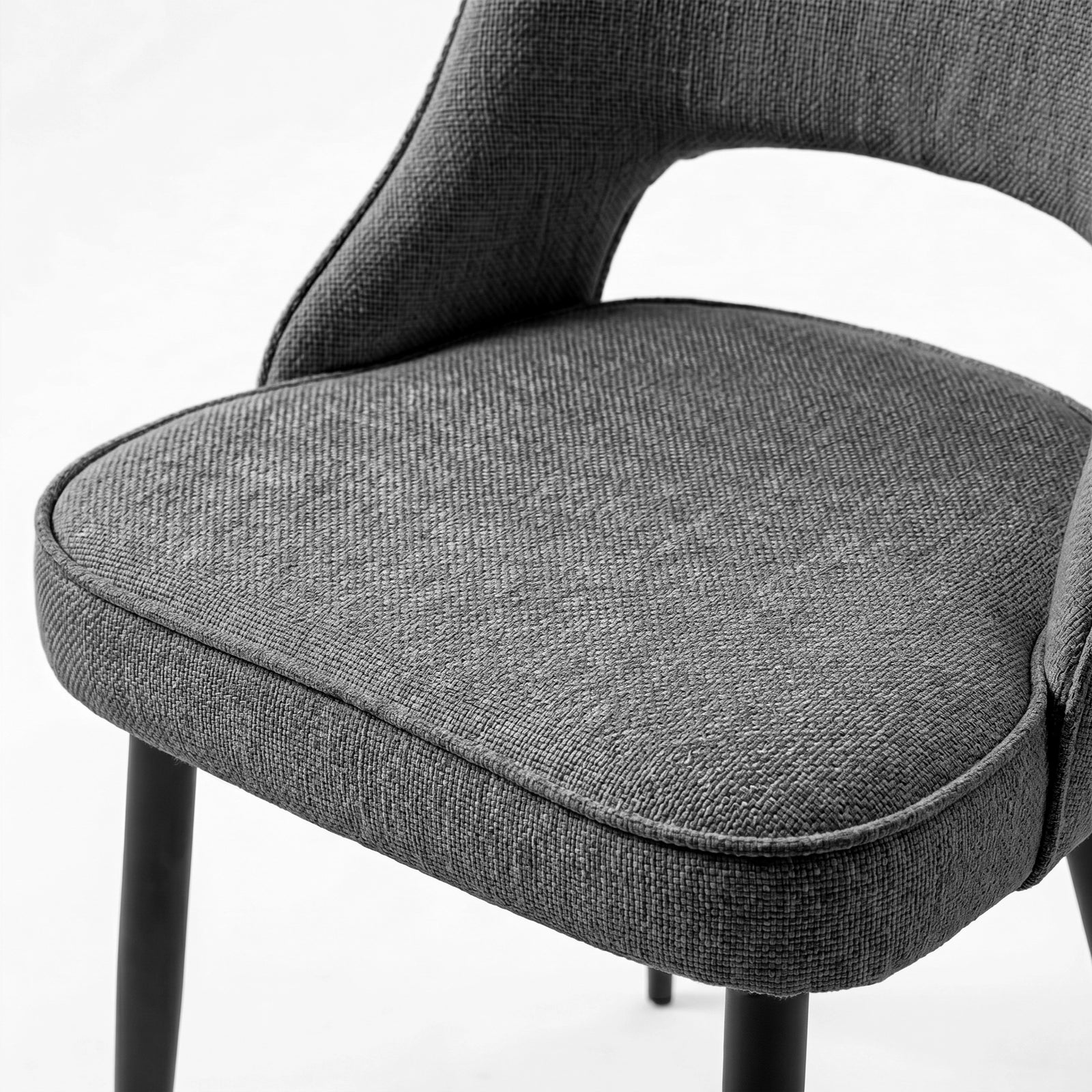 [Grey | Set of 4] Comfy dining chair close-up of fabric padded seat, piped edge, curved open back & black metal legs