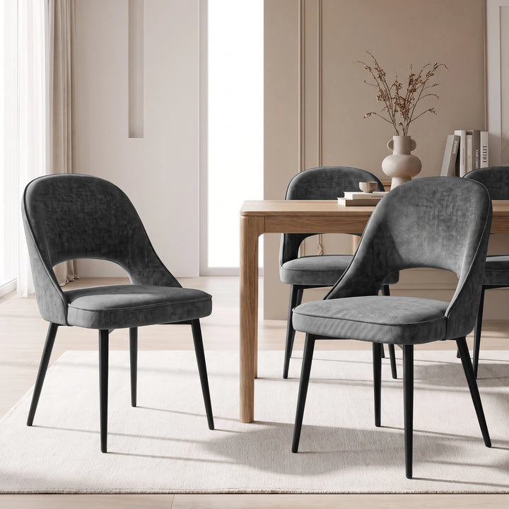 [Grey | Set of 4] Pair of fabric dining room chairs at a wooden table, showing curved open backs and black metal legs