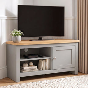 [Grey] TV stand with a light wood top, shown in a styled room setting with a flat-screen TV, a small potted plant, and decorative items on and inside the shelves