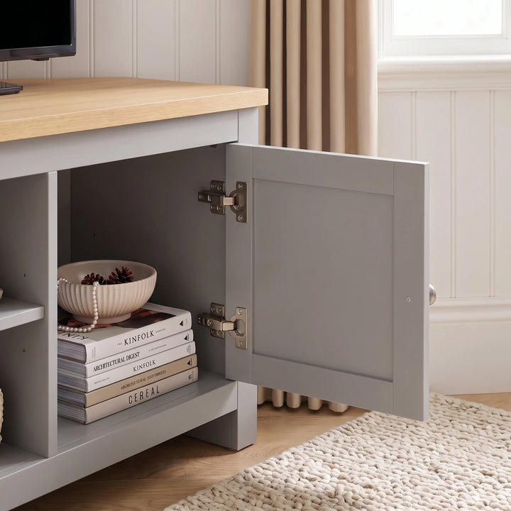 [Grey] corner tv unit with a light wood top, shown with its front door open to reveal storage space
