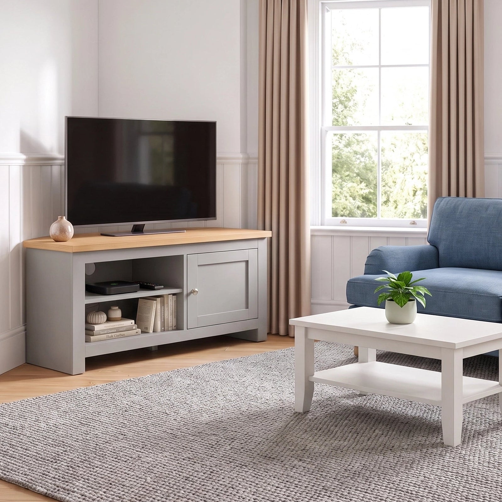 [Grey] A living room scene showing a blue sofa, white coffee table, grey rug, and a grey TV stand with a television, set in a bright room with beige curtains and wood flooring.