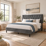 [Double | Grey] Angled bed view showing a tufted headboard, layered bedding, wooden bedside tables, window, and woven rug.