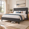 [Double | Grey] Angled bedroom view showing a robot vacuum beneath the bed frame, tufted headboard, bedding, and woven rug.