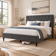 [Double | Grey] Angled bedroom view showing a robot vacuum beneath the bed frame, tufted headboard, bedding, and woven rug.