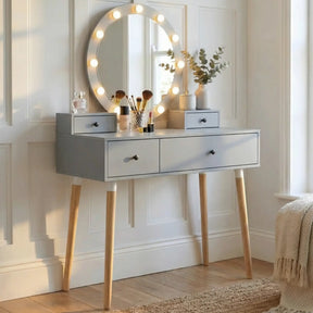 [Grey] Dressing Table With Drawers styled with perfume bottles, makeup brushes, eucalyptus stems, and illuminated Hollywood mirror in a panelled room