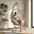 [Grey] Woman sitting in a hanging egg chair in a bright room with plants and shelves