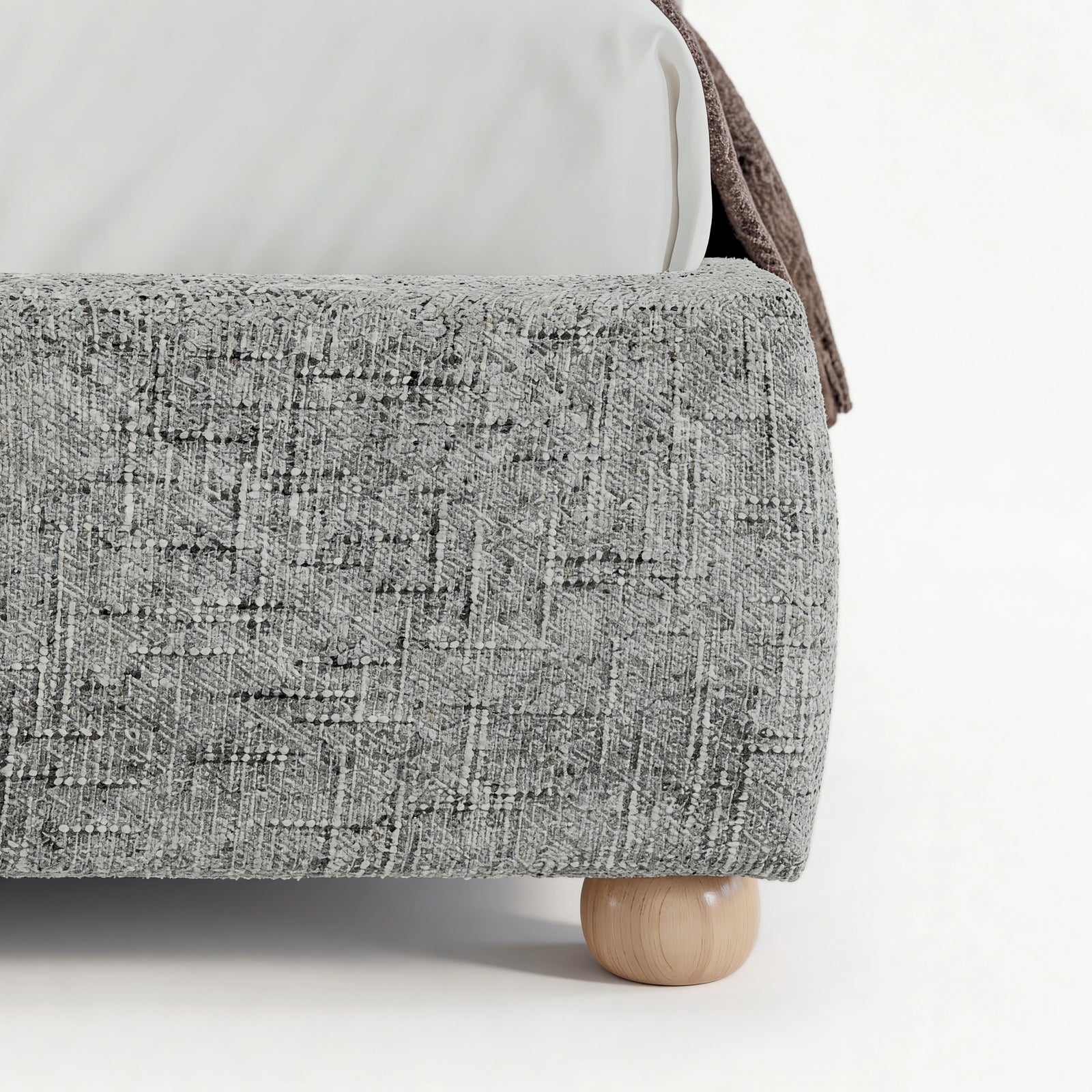 [King | Grey] Embracea bed base close-up showing curved footboard profile, woven fabric texture, and solid oak round leg