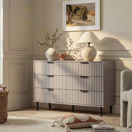 [Grey] Flutrina dresser in a neutral room setting with framed artwork, table lamp and accent chair