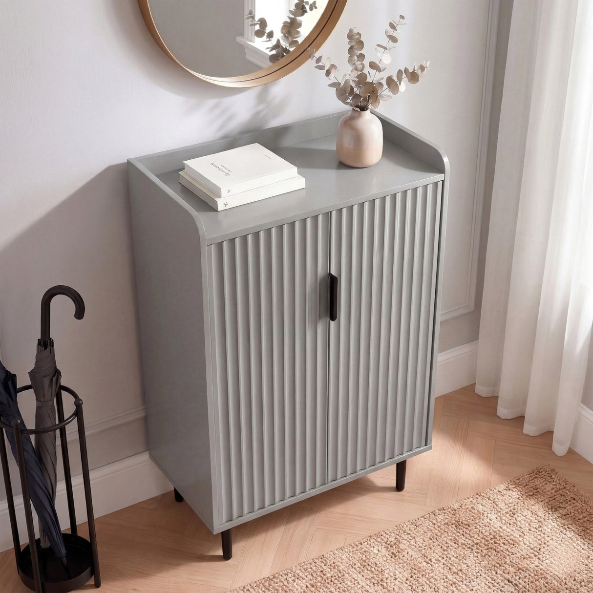 [Grey] Flutrina shoe cabinet front view with doors closed on herringbone flooring with a round gold mirror above