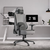Xstriker Ergonomic Fabric Reclining Gaming Chair with 4D Armrest for Adults in grey, placed in a modern home office setup with a desktop computer and accessories.