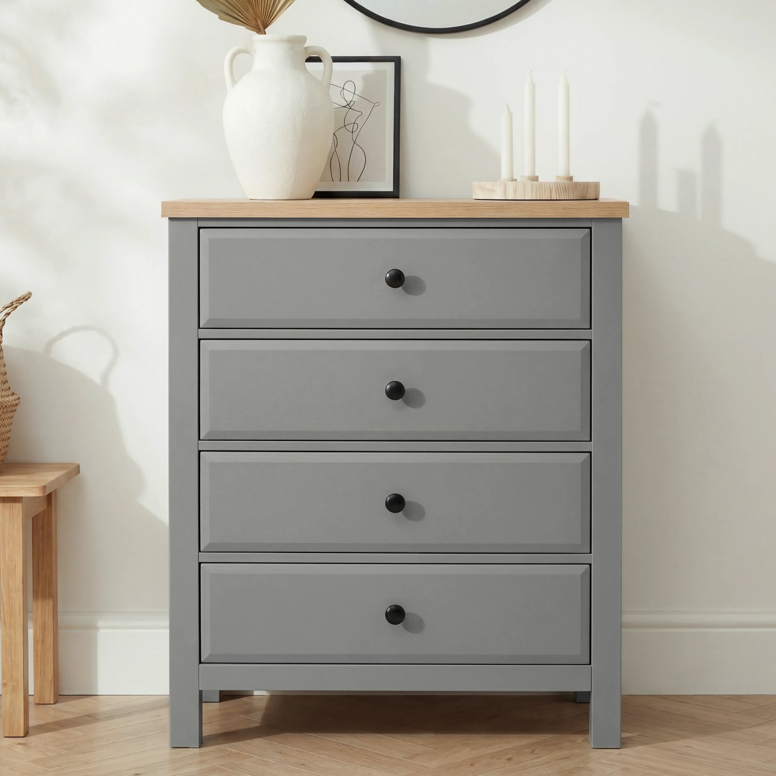 [Grey] Haven 4 drawer chest straight-on against a white wall with a tall white pitcher and framed line-art print on top