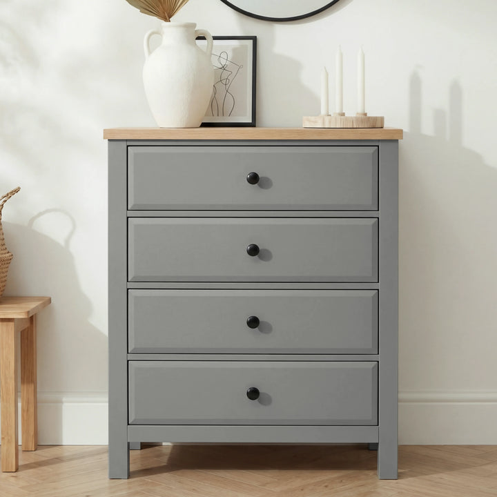 [Grey] Haven 4 drawer chest straight-on against a white wall with a tall white pitcher and framed line-art print on top