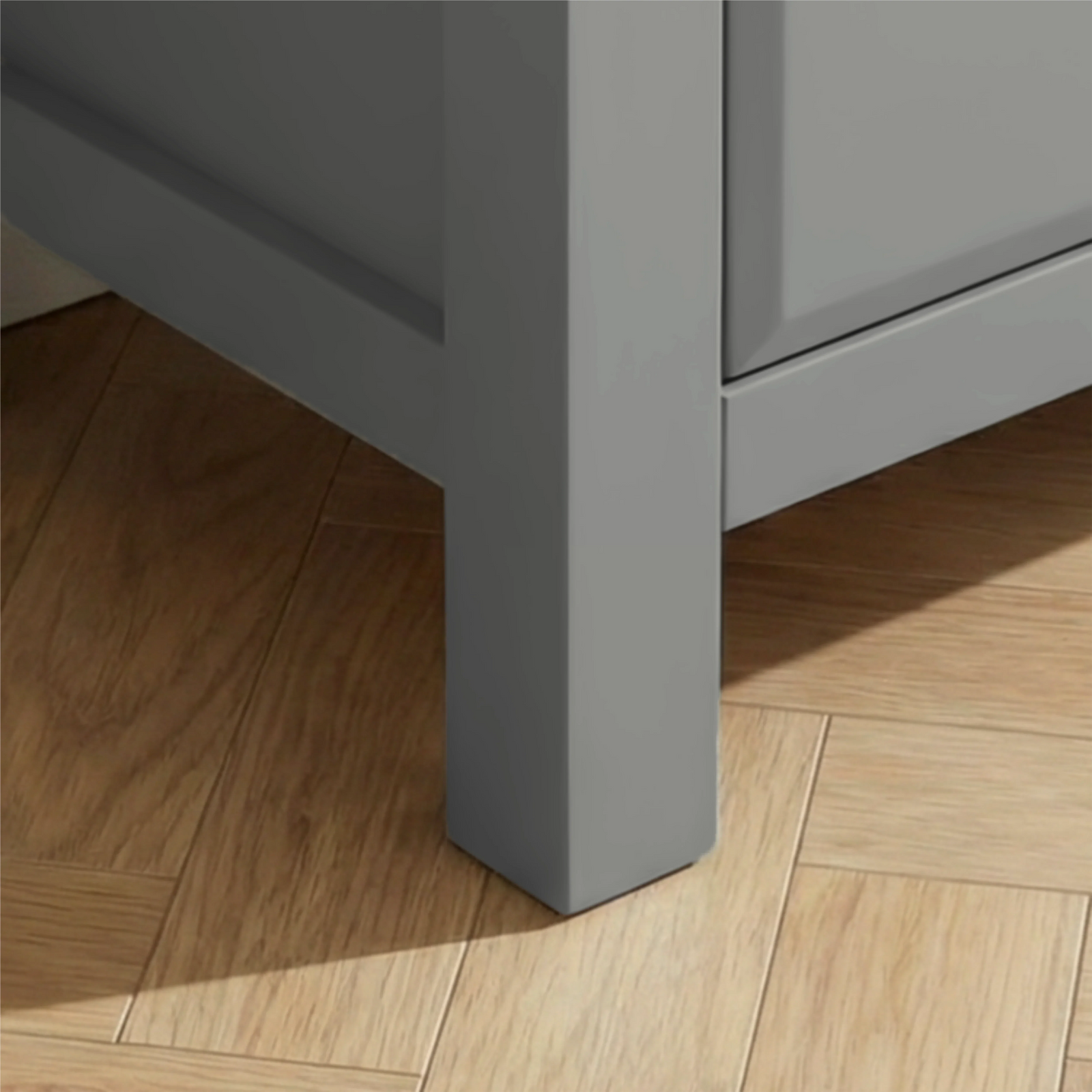 [Grey] Haven chest close-up of the solid square grey painted leg resting on warm oak herringbone parquet flooring