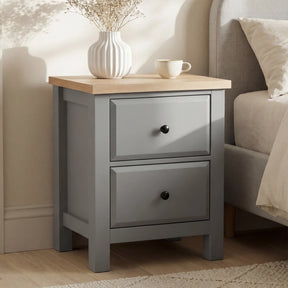 [Grey] Haven bedside table styled beside a linen upholstered bed with dried flowers and mug on oak top