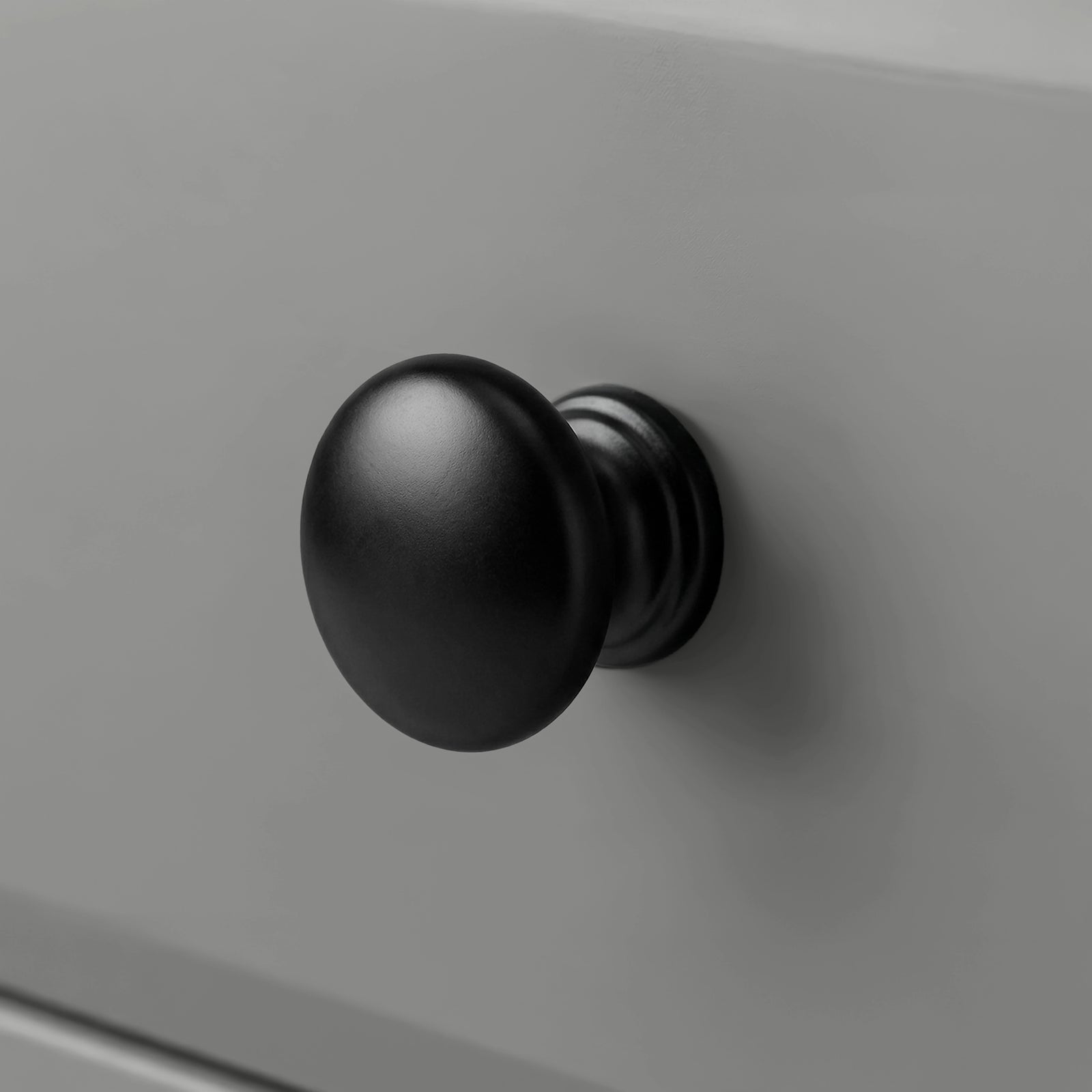 [Grey] Haven close detail of black round knob on smooth drawer front with softly bevelled panel edge