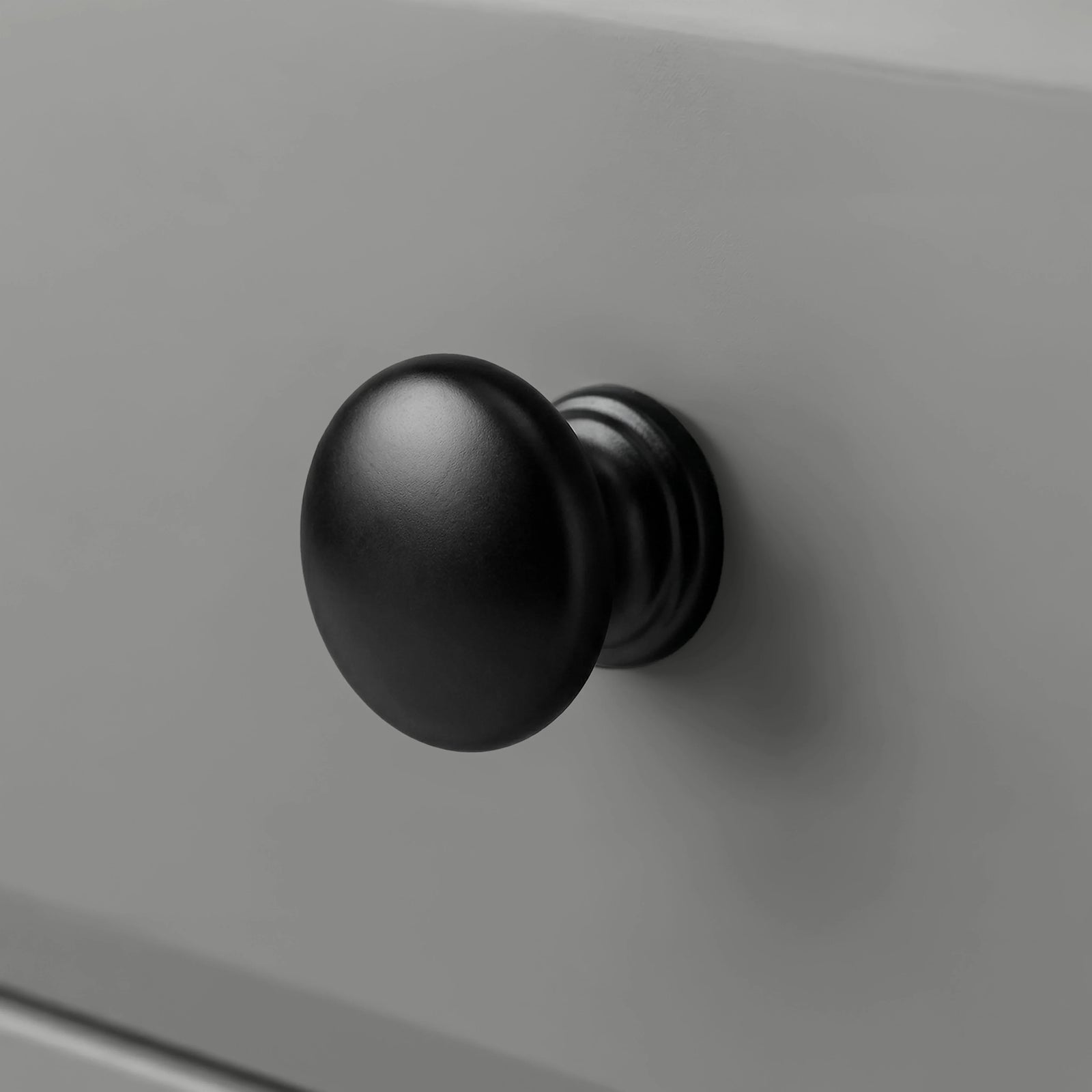 [Grey] Haven close detail of black round knob on smooth drawer front with softly bevelled panel edge