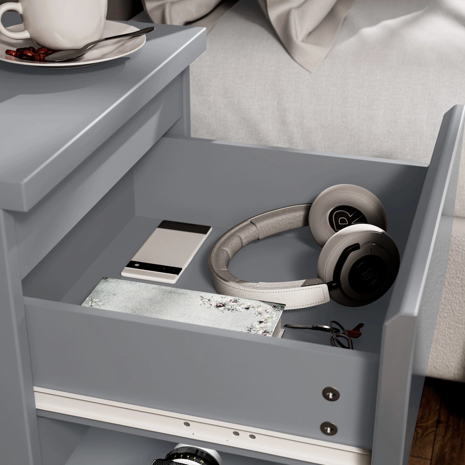 [Grey] close-up of open drawer in grey bedside table showing phone headphones notebook and keys