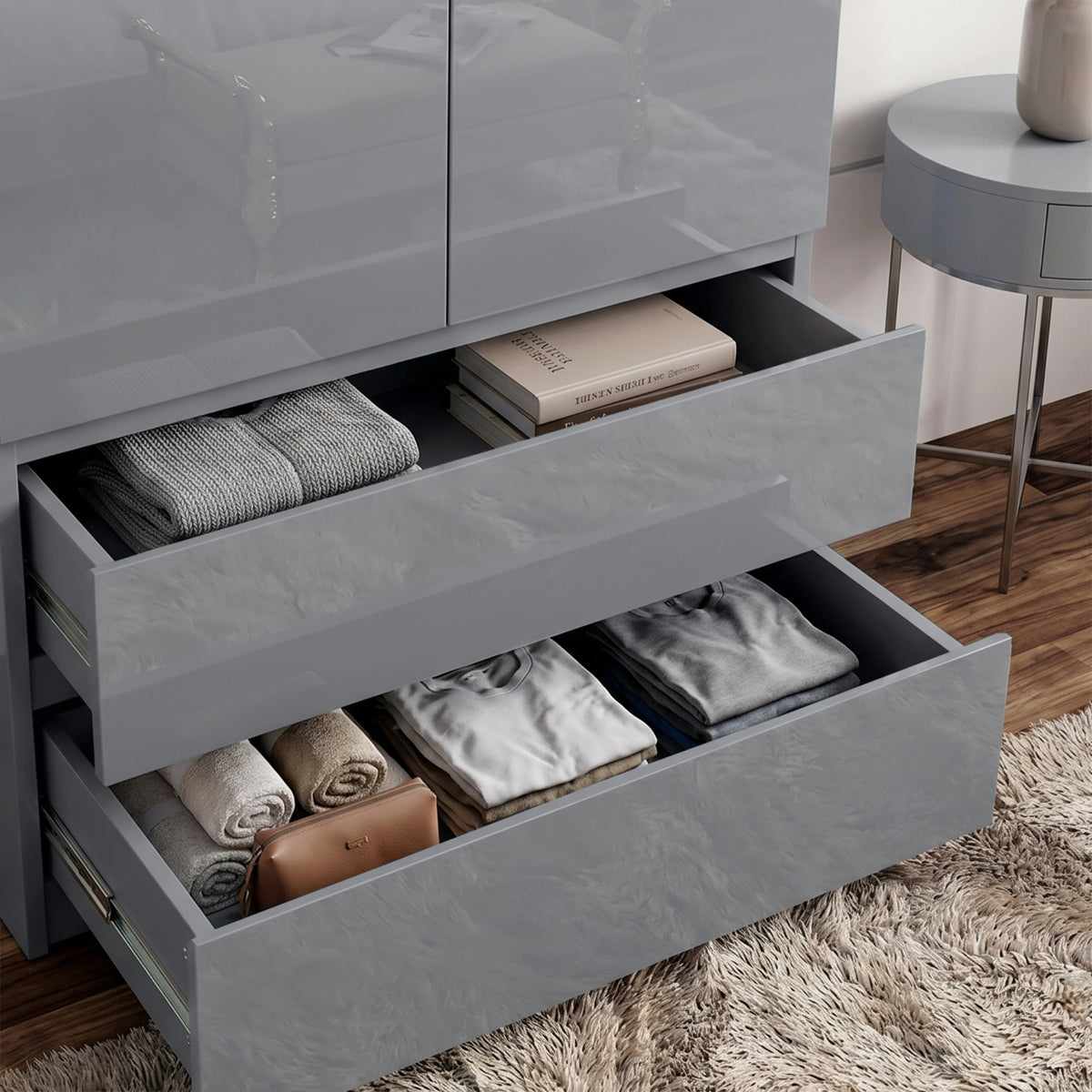 [Grey] High gloss wardrobe drawer detail showing folded clothes, towels, books, side table, wood floor, and rug.
