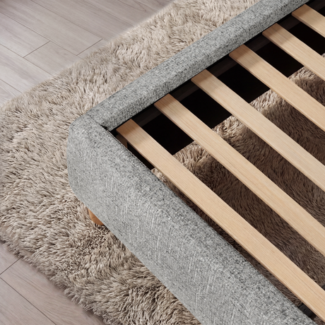 [King | Grey] Angled view of a grey king fabric-wrapped upholstered bed base corner with exposed wooden slats