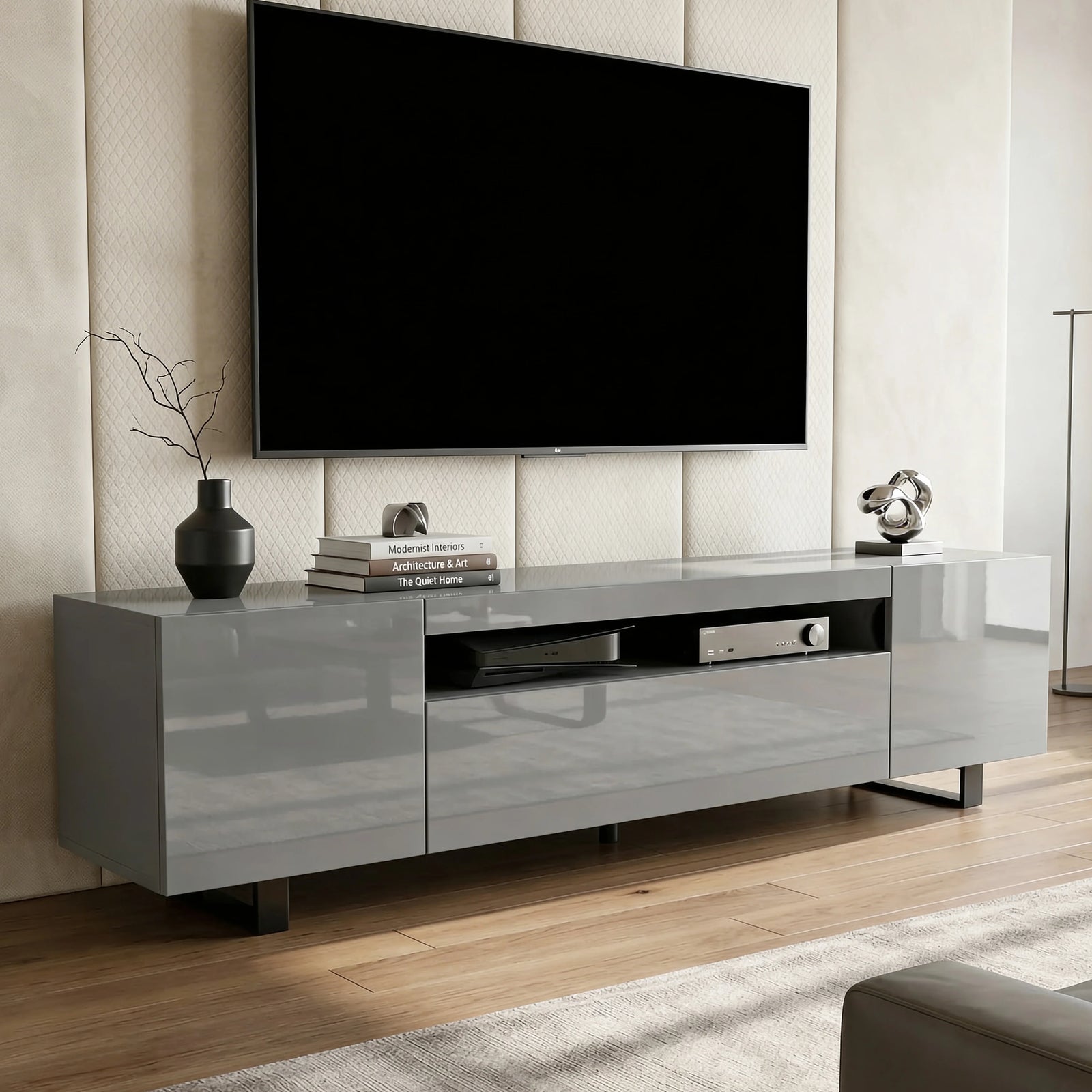 [Grey] Kystra TV stand with wall-mounted black TV above on a panelled wall, vase, books and small sculpture on gloss top