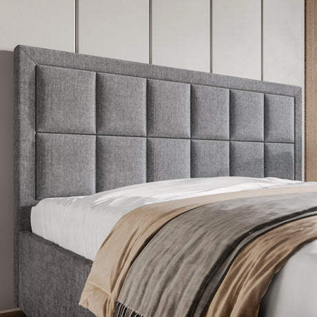 Gray upholstered headboard with a bed and beige blanket against a neutral wall.