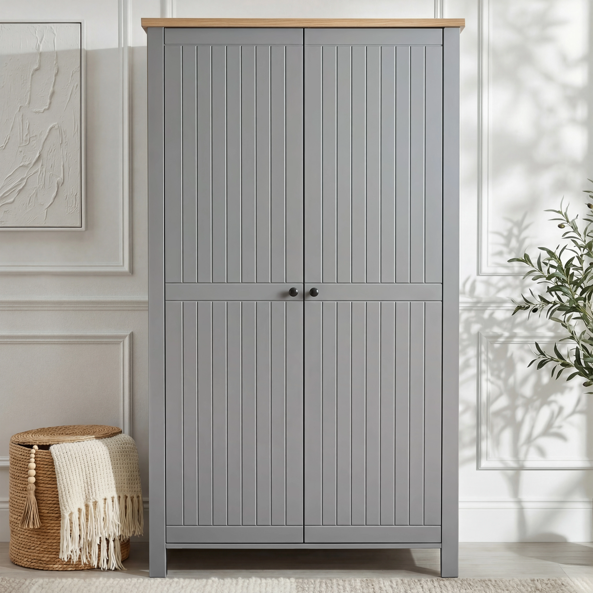 [Grey] Linra 2 Door Wardrobe front view in a white panelled room with woven basket and throw beside it and olive tree to the right