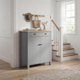 [Grey] Linra Grey 4 Tier Painted Shoe Storage Cabinet With Drawer three-quarter view in styled hallway with staircase, coat hooks and flowers on oak top