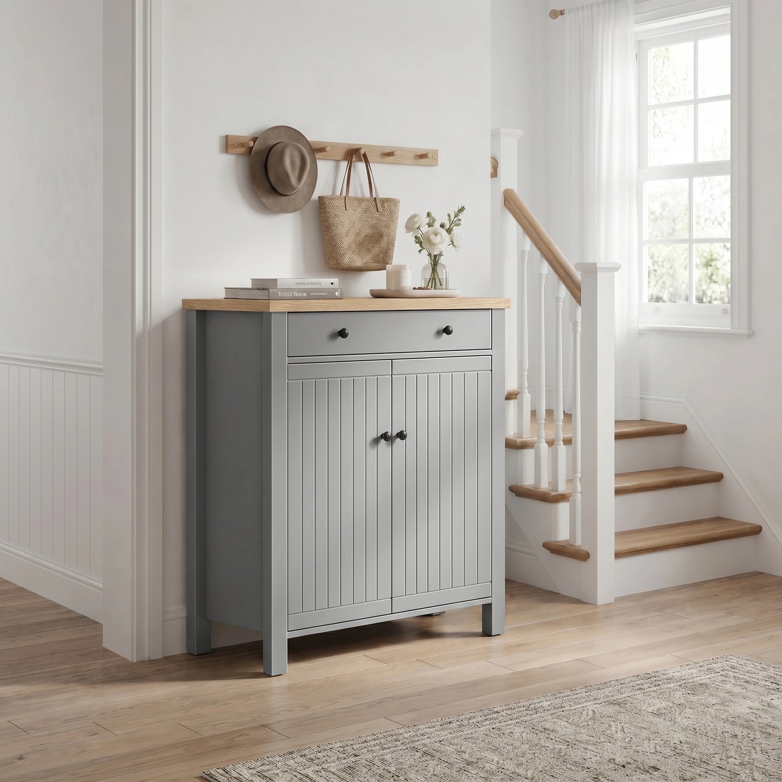 [Grey] Linra Grey 4 Tier Painted Shoe Storage Cabinet With Drawer three-quarter view in styled hallway with staircase, coat hooks and flowers on oak top