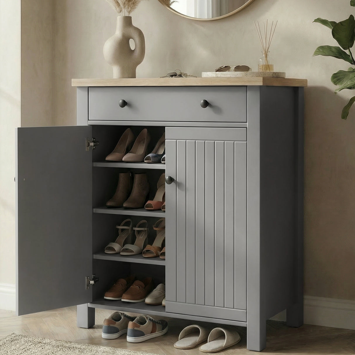 [Grey] Linra shoe cabinet with left door open showing four shelves holding heels, boots, and sandals in a warm hallway