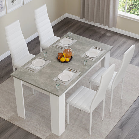 4 seater grey marble dining table set with white chairs in a stylish dining room with wall art and chandelier.