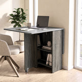 [Grey] Compact folding dining table used as a desk, with one marble-effect leaf raised and rod-fronted shelves on wheels.