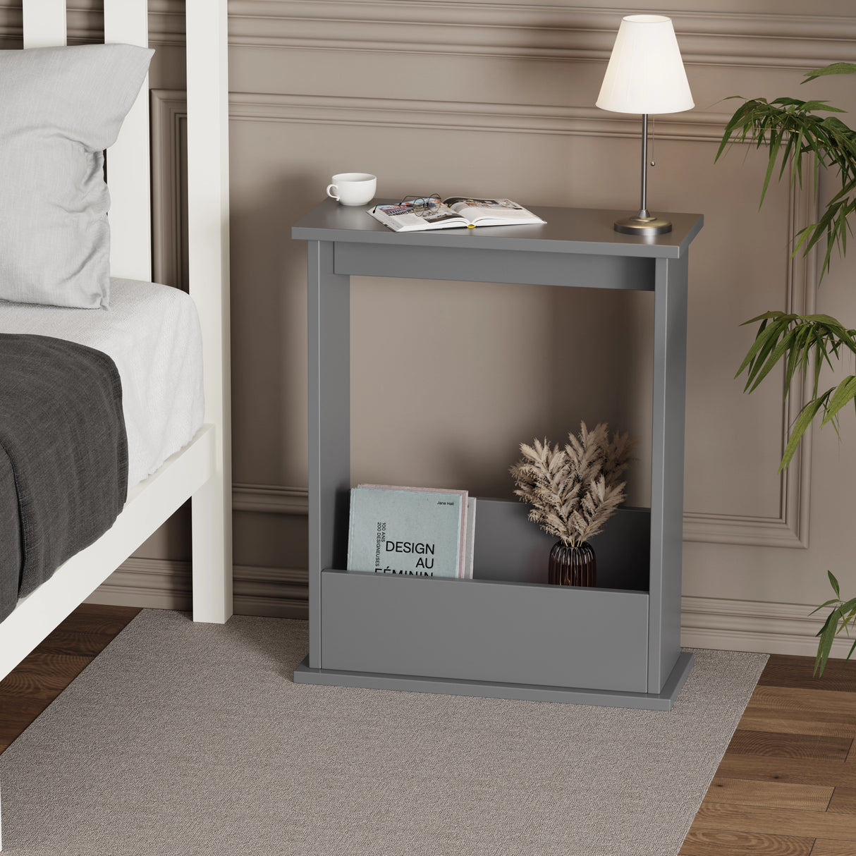 Grey slim and small side table with oak top used as nightstand in bedroom with books in slot and warm light on top.