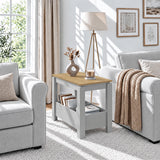 [Grey] Sunlit living room with a side table between two seats, a vase on the wood-effect top and books below.