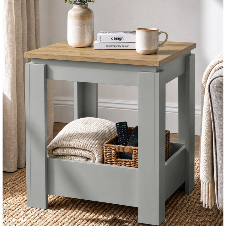 [Grey] Angled view of the square side table beside a sofa, with a folded throw and basket in the open lower storage