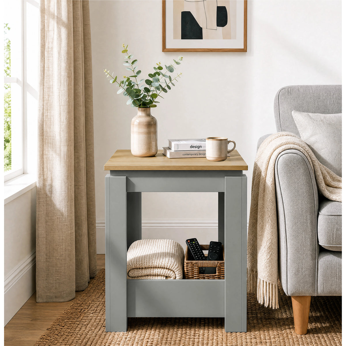 [Grey] Front view of the square side table beside a sofa, with a folded throw and basket stored below