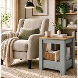 [Grey] Square side table in a living room beside an armchair, with a basket, books and throw stored below