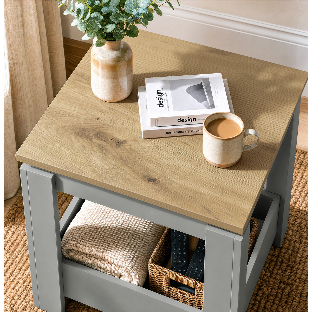 [Grey] High-angle view of the square side table top and lower storage with a basket and folded throw