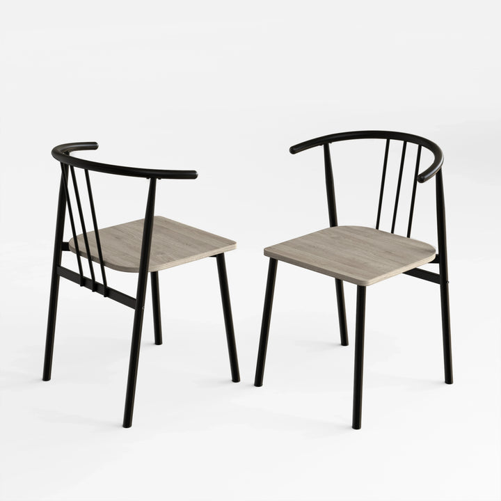[Grey Oak] Two Torvi dining chairs on white background showing black curved metal frame and grey oak wood seats