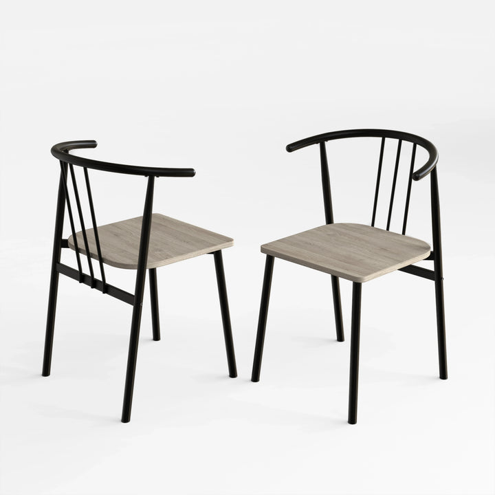 [Grey] Two Torvi dining chairs on white background showing black curved metal frame and grey oak wood seats