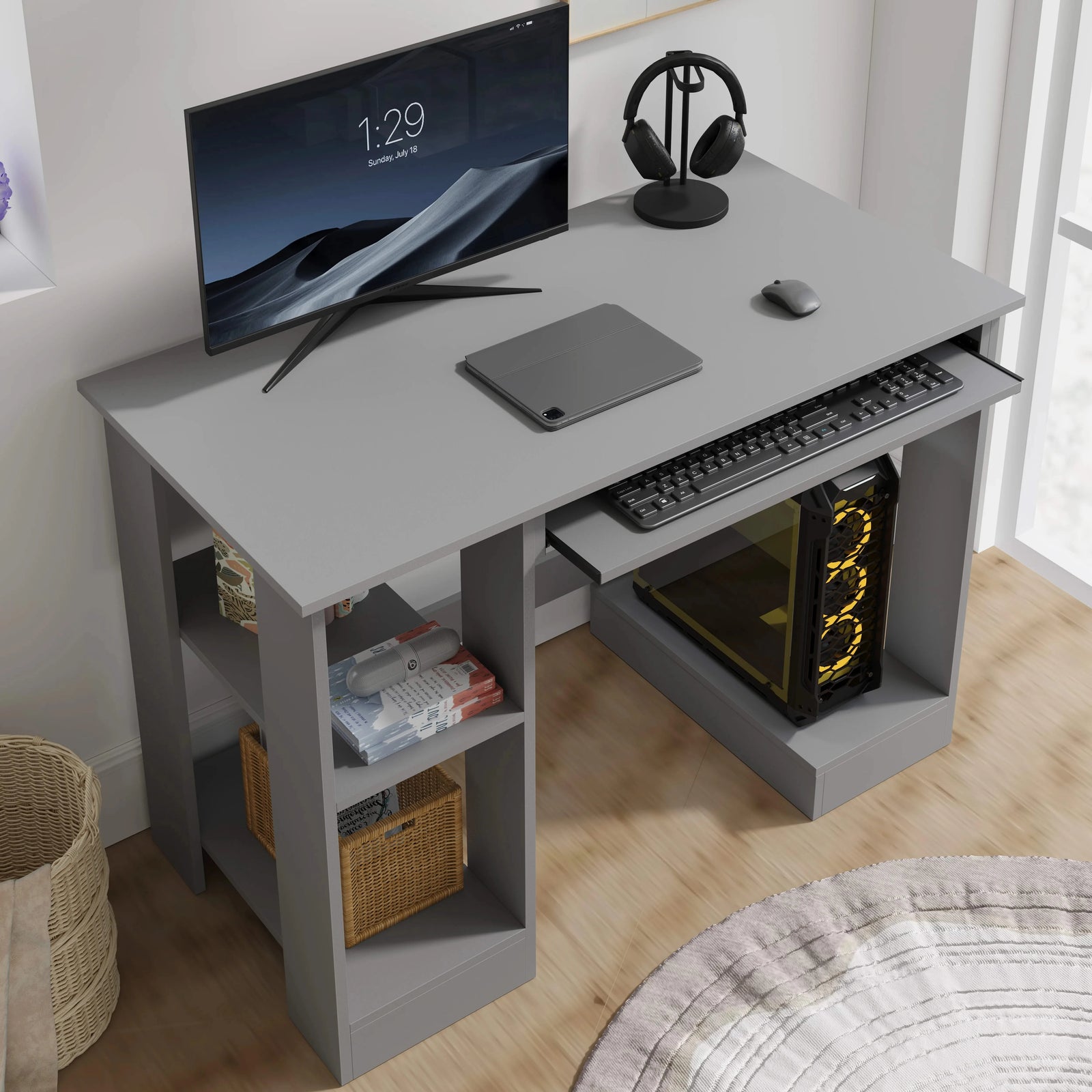 [Grey] Angled grey computer desk view showing monitor, mouse, pull-out keyboard tray and gaming PC tower below