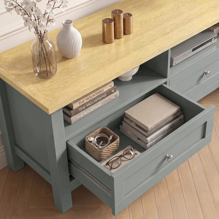 [Grey] Oskara TV unit viewed from above with one drawer open storing cables, glasses, and wicker tray beside open shelf with books and media player